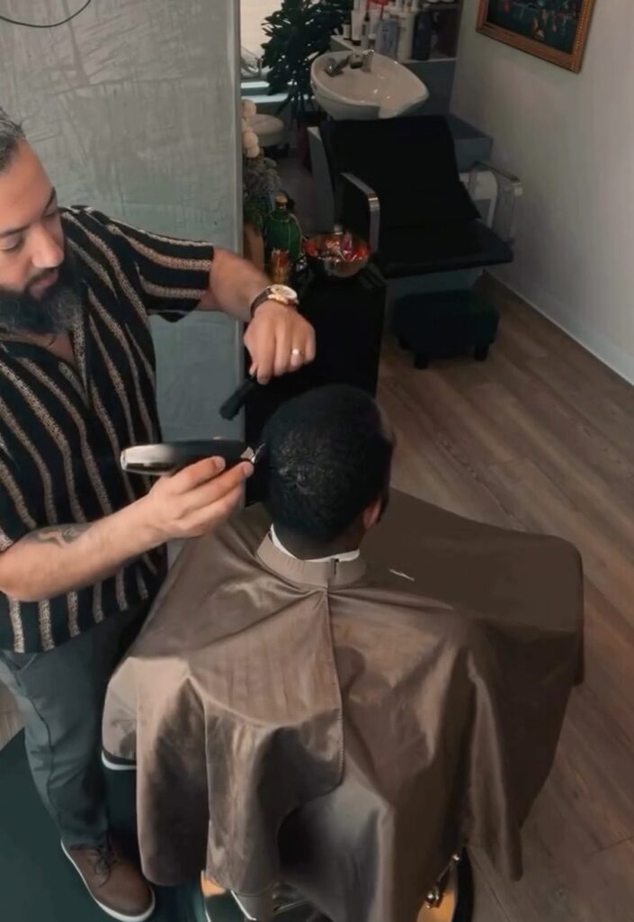 Barber giving a client a clipper cut in his private salon suite in Fort Worth, filling an open slot from his standby list